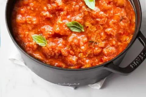 Pappa al pomodoro fumante in una pentola scura, guarnita con foglie di basilico fresco. Un classico comfort food toscano.