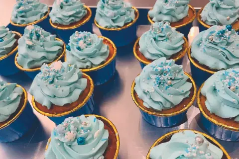 Una fila di cupcake con glassa azzurra e decorazioni a tema invernale. Una deliziosa cupcake ricetta pronta da gustare.