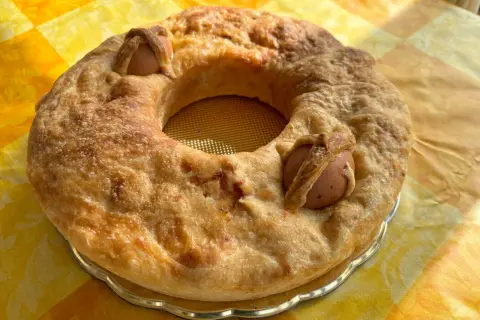 Casatiello napoletano dorato, con uova intere incastonate nell'impasto, pronto per essere gustato.