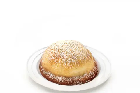 Sfogliatella frolla, un dolce napoletano dalla forma a conchiglia, cosparso di zucchero a velo su un piatto bianco.