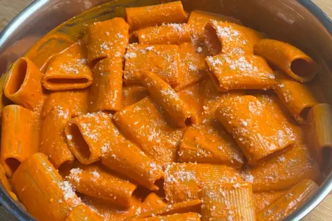 Rigatoni cremosi in salsa all'nduja, cosparsi di formaggio grattugiato. Un piatto invitante e saporito.