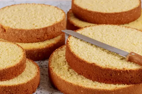 Dischi di pan di spagna dorati e soffici, pronti per essere farciti. Un coltello da torta è appoggiato su uno strato.