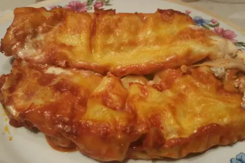 Cannelloni ricotta e carne gratinati al forno, con sugo rosso e formaggio filante.