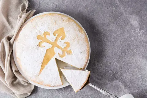 Una fetta di torta di Santiago, cosparsa di zucchero a velo, con la tipica croce incisa.