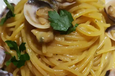 Spaghetti alle vongole cremosi come al ristorante, un piatto invitante con pasta dorata, vongole succulente e prezzemolo fresco.