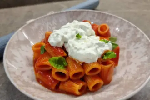 Rigatoni al sugo con abbondante stracciatella cremosa e basilico fresco. Un piatto semplice ma delizioso.