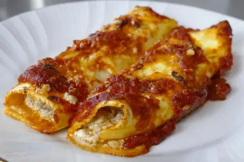 Due cannelloni di carne ripieni e ricoperti di sugo rosso, serviti su un piatto bianco.