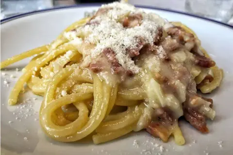 Un piatto di spaghetti alla carbonara, cremosi e ricchi di guanciale croccante, spolverati di pecorino.