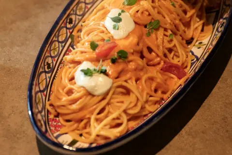 Un invitante piatto di pasta con pomodorini, condita con una cremosa salsa e guarnita con ricotta fresca e basilico.