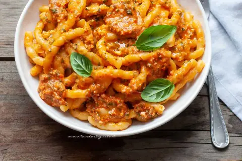 Busiate alla trapanese, pasta fresca con sugo rosso e basilico, un piatto ricco di sapori mediterranei.