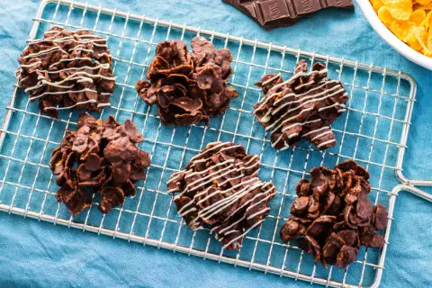 Sei deliziose rose del deserto al cioccolato, alcune decorate con glassa bianca, riposano su una griglia.
