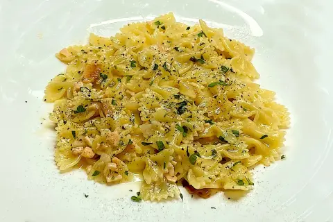 Farfalle condite con cubetti di salmone rosa, prezzemolo tritato e pepe nero. Un piatto di pasta al salmone invitante.