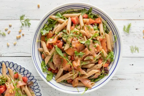Pasta fredda con salmone affumicato, pomodorini, rucola e olive nere. Un piatto estivo leggero e gustoso.