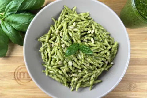 Piatto di trofie al pesto, guarnite con pinoli e basilico fresco. Un classico delle trofie ricette, pronto da gustare.
