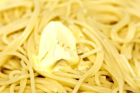 Un piatto di pasta in bianco fumante, con una generosa noce di burro che si scioglie lentamente tra gli spaghetti.