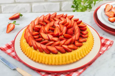 Deliziosa crostata di fragole, con una base dorata e un ripieno cremoso, ricoperta da fragole fresche affettate.