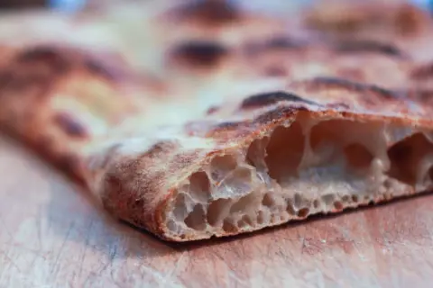 La pizza bonci, con la sua alveolatura perfetta e la crosta dorata, è un'opera d'arte culinaria.