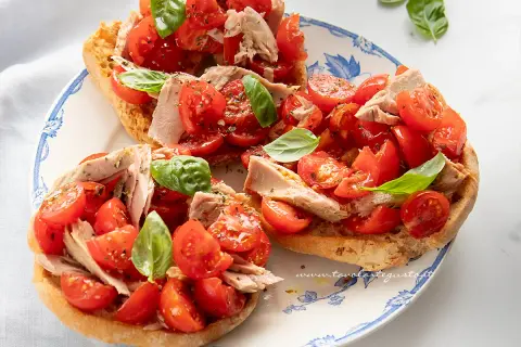 Friselle con pomodorini freschi, tonno e basilico, un piatto estivo leggero e gustoso.