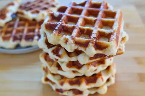 Una pila di waffle dorati, con la loro tipica griglia, che ricordano la waffle ricetta originale belga.