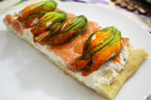 Focaccia con fiori di zucca, salmone affumicato e ricotta. Un piatto colorato e gustoso.