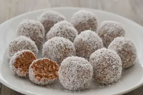 Dolci palline di cocco, una delizia da gustare in ogni momento. Una è stata aperta, rivelando il suo interno morbido e invitante.