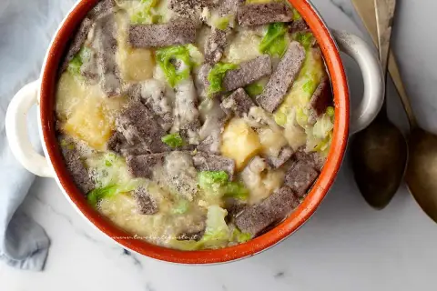 Pizzoccheri ricetta: un piatto fumante in una casseruola con pasta di grano saraceno, patate, verza e formaggio fuso.