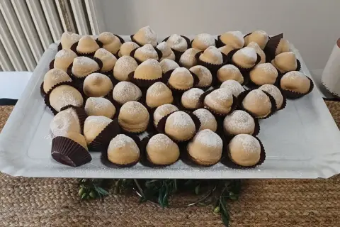 Dolcetti "tette delle monache" spolverati di zucchero a velo, un'antica ricetta che narra storie di conventi e sapori autentici.
