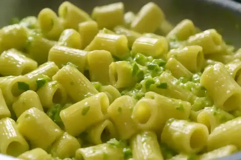 Rigatoni conditi con una cremosa salsa verde, un delizioso piatto di pasta e zucchine alla napoletana.
