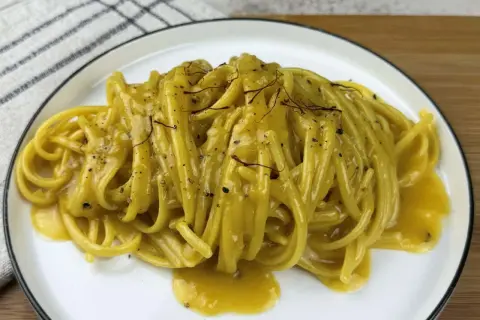 Un piatto di pasta alla milanese cremosa, con fili di zafferano e pepe nero.