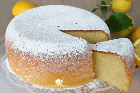 Torta al limone morbidissima e profumatissima benedetta, cosparsa di zucchero a velo. La fetta tagliata rivela la sua sofficità.