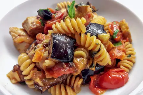 Fusilli con pesce spada, melanzane, pomodorini e basilico, un piatto estivo saporito.