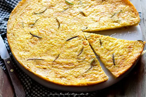 Dorata farinata di ceci in padella, guarnita con rosmarino fresco, pronta per essere gustata.
