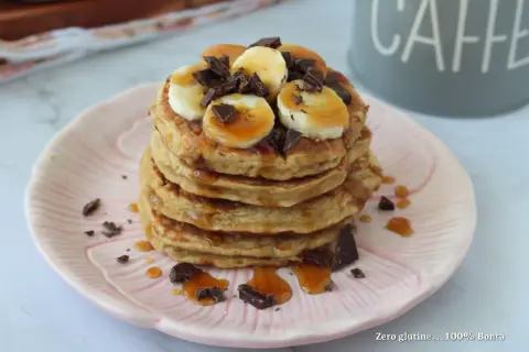 Pancake banana e yogurt, una pila golosa con scaglie di cioccolato e sciroppo d'acero.