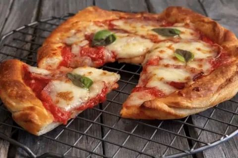 Pizza in friggitrice ad aria, croccante e filante, con pomodoro e mozzarella, guarnita con basilico fresco.