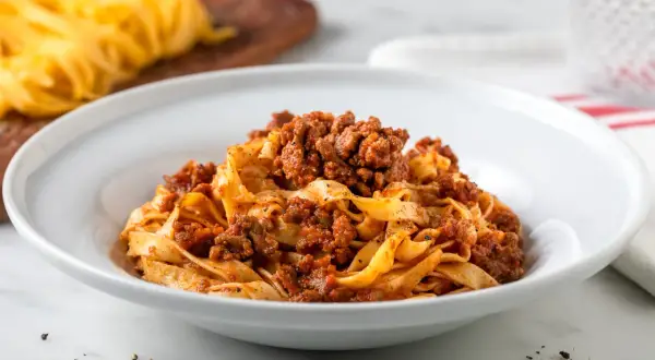Tagliatelle al ragù, un classico delle ricette italiane, servite in un piatto bianco.