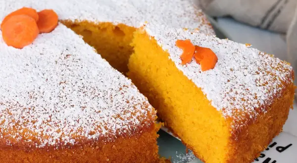 Torta Camilla, ricetta originale: soffice torta all'arancia e carota, spolverata di zucchero a velo e decorata con fettine di carota.