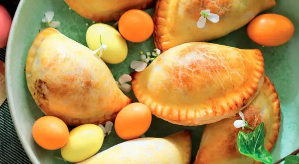 Nepitelle calabresi ricetta originale: dolcetti dorati ripieni, decorati con uova colorate e fiori, un'esplosione di sapori autentici.