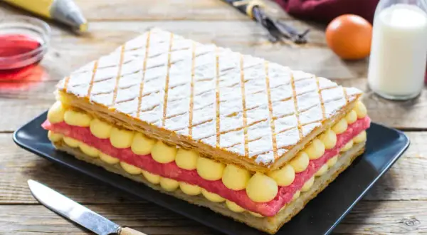 Una deliziosa torta diplomatica, con strati di pasta sfoglia, crema pasticcera e fragole, pronta per essere gustata.