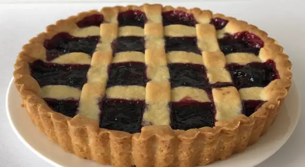 Una deliziosa crostata di marmellata con una griglia di pasta dorata e un ripieno scuro e invitante.