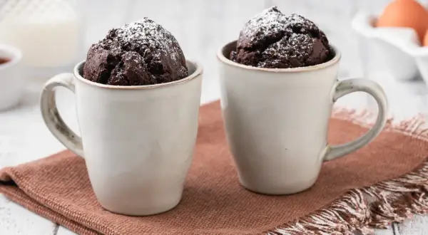 Due mug cake al cioccolato, spolverati di zucchero a velo, pronti per essere gustati.