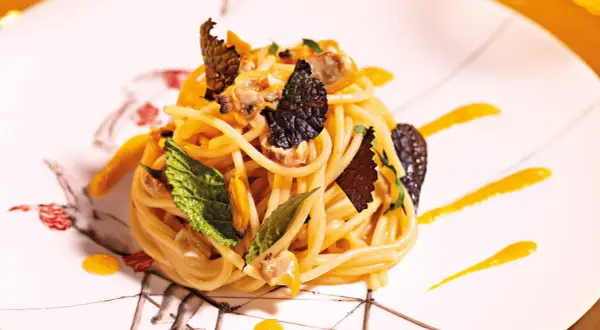 Spaghetti con frutti di mare, guarniti con foglie di menta e scaglie di tartufo. Un'idea su come cucinare la pasta in modo elegante.
