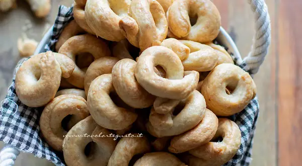 Un cesto pieno di taralli pugliesi ricetta originale, dorati e croccanti, pronti per essere gustati.