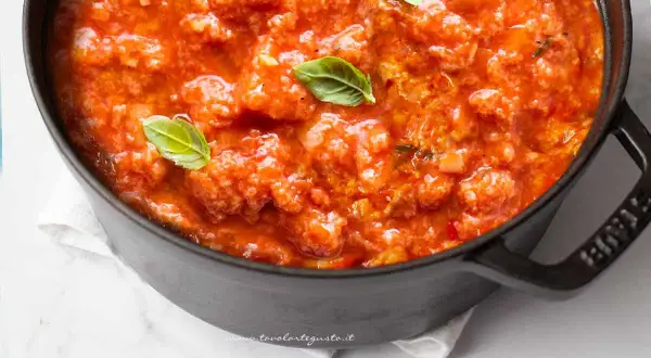 Pappa al pomodoro fumante in una pentola scura, guarnita con foglie di basilico fresco. Un classico comfort food toscano.