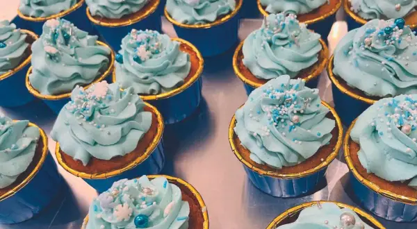 Una fila di cupcake con glassa azzurra e decorazioni a tema invernale. Una deliziosa cupcake ricetta pronta da gustare.