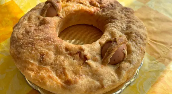 Casatiello napoletano dorato, con uova intere incastonate nell'impasto, pronto per essere gustato.