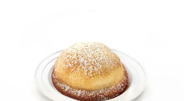 Sfogliatella frolla, un dolce napoletano dalla forma a conchiglia, cosparso di zucchero a velo su un piatto bianco.