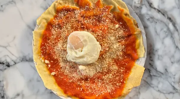 Piatto con pane carasau, salsa di pomodoro, formaggio grattugiato e uovo in camicia. Un'idea per gustose ricette.