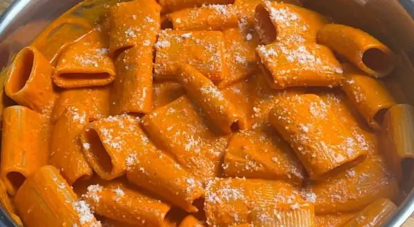 Rigatoni cremosi in salsa all'nduja, cosparsi di formaggio grattugiato. Un piatto invitante e saporito.