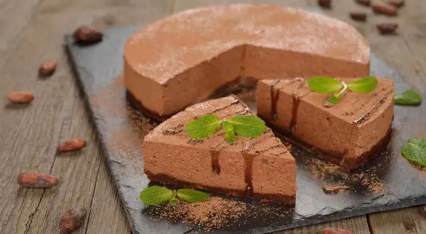 Deliziosa bavarese al cioccolato, spolverata di cacao e decorata con menta fresca. Un dolce invitante su una lavagna scura.