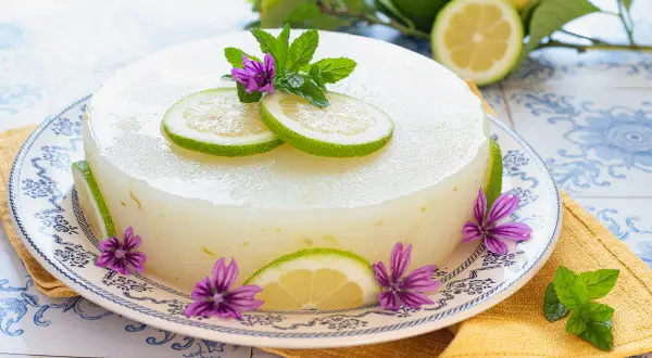 Delizioso gelo di limone decorato con fette di limone, fiori viola e foglie di menta.